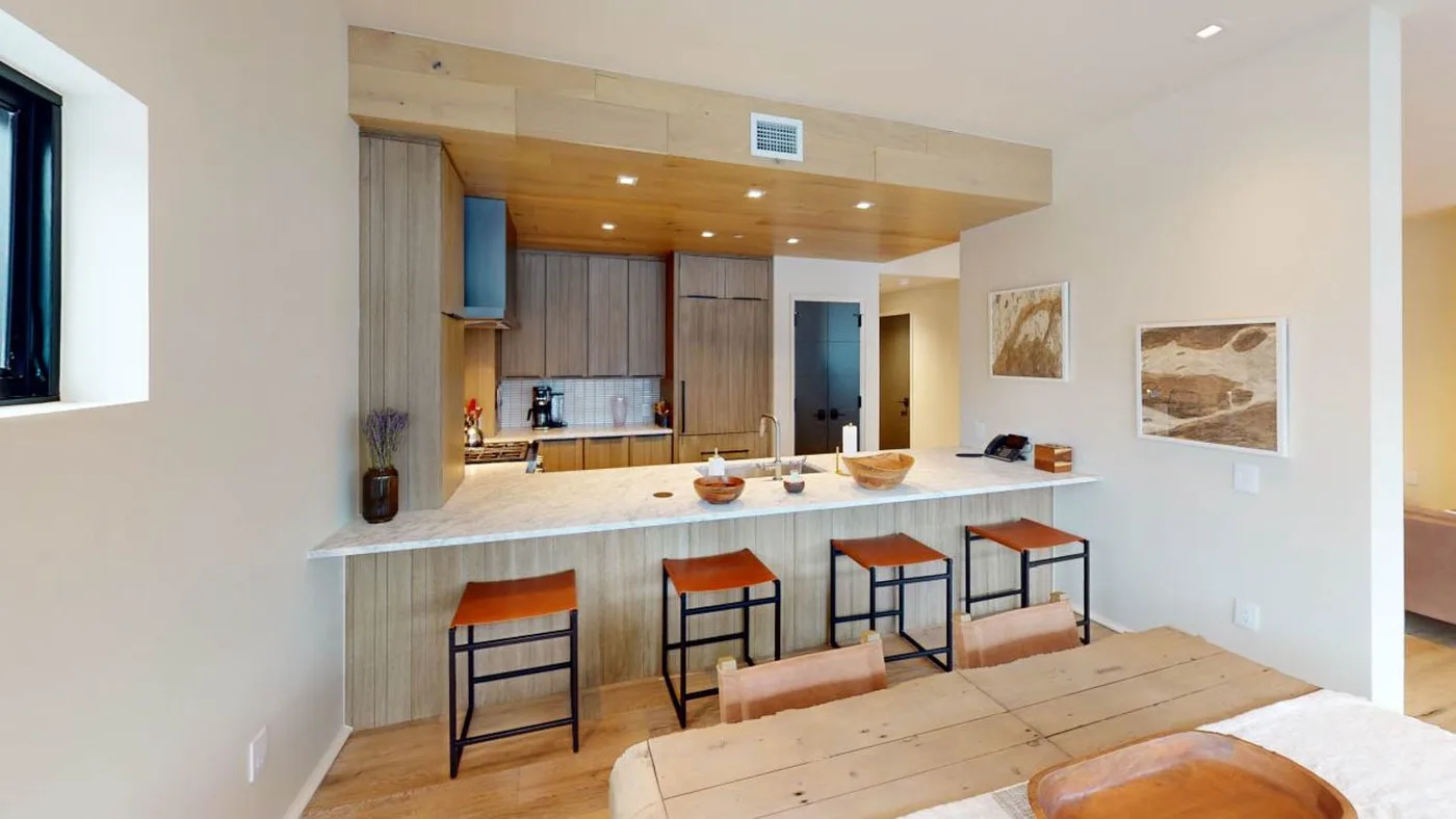 Cocina y comedor abiertos con una barra larga y una mesa de madera.