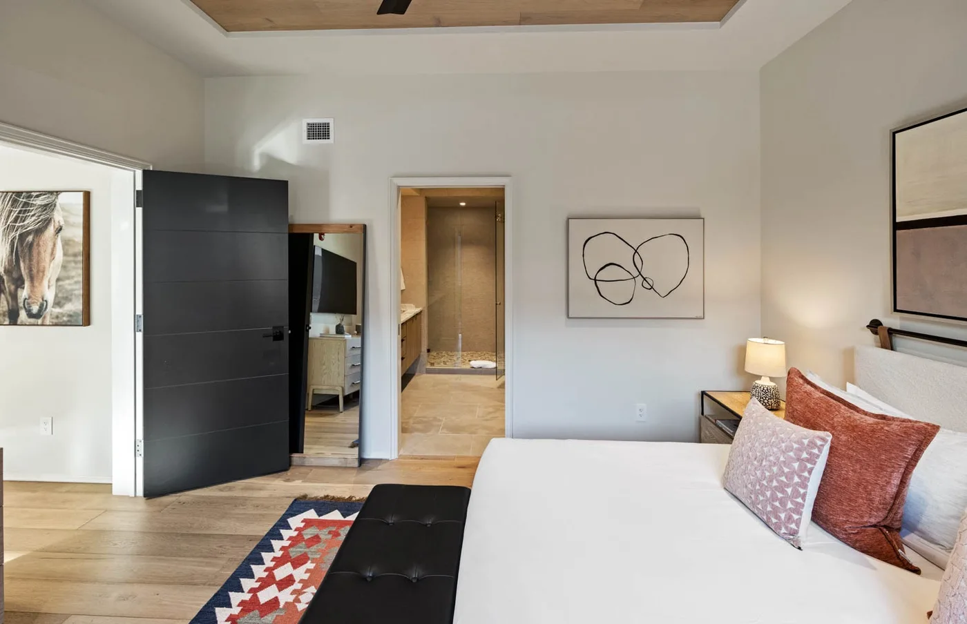 Un dormitorio con una cama grande, una puerta abierta y cuadros en la pared.