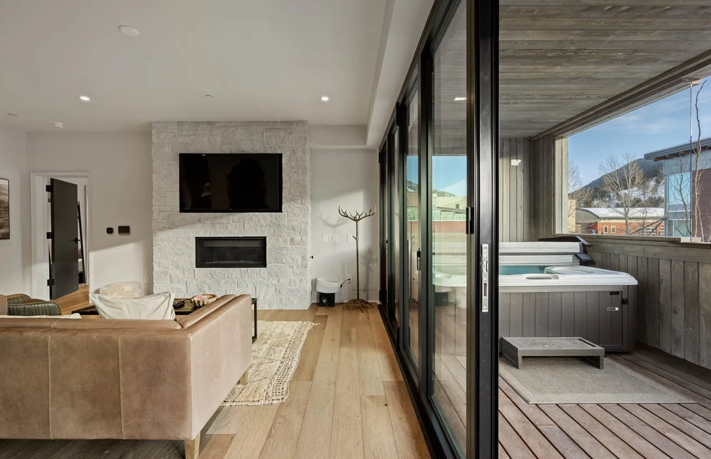 Una luminosa sala de estar se abre a un patio cubierto con una bañera de hidromasaje y vistas a las montañas.