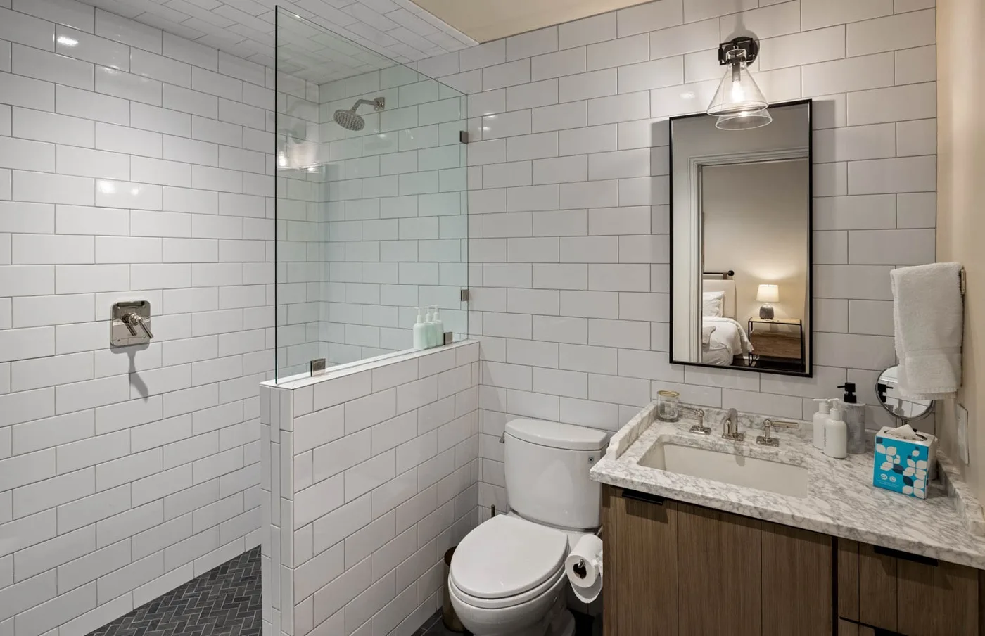 Un baño revestido de azulejos con ducha de vidrio, inodoro y lavabo.