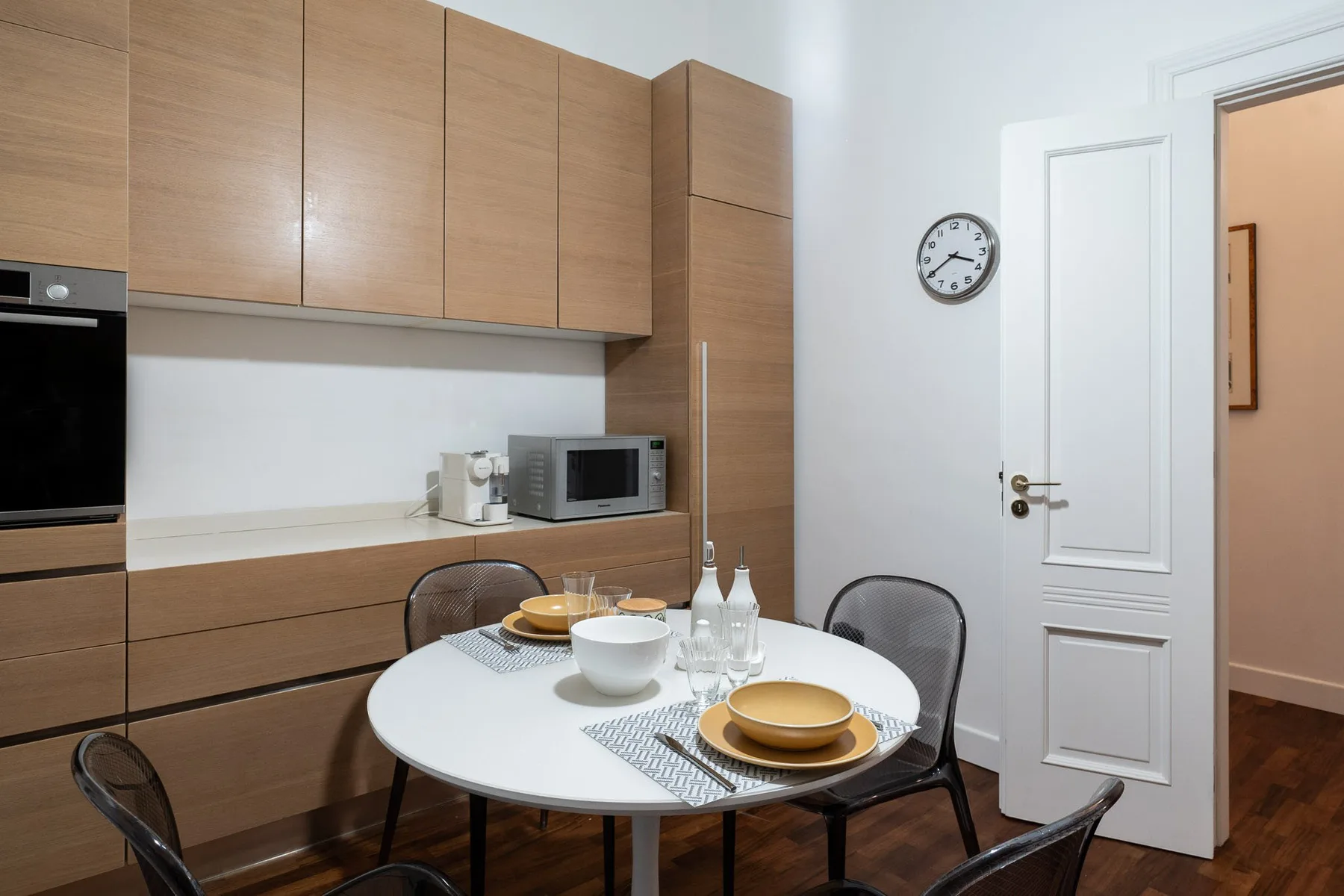 Un comedor con una mesa redonda con platos junto a armarios de madera.