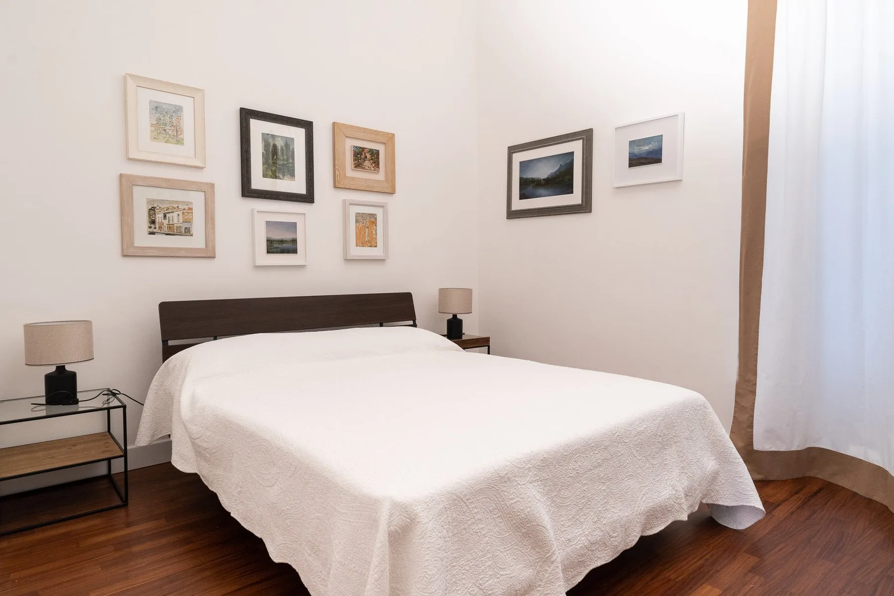 Un dormitorio con una cama tendida y cuadros en las paredes.