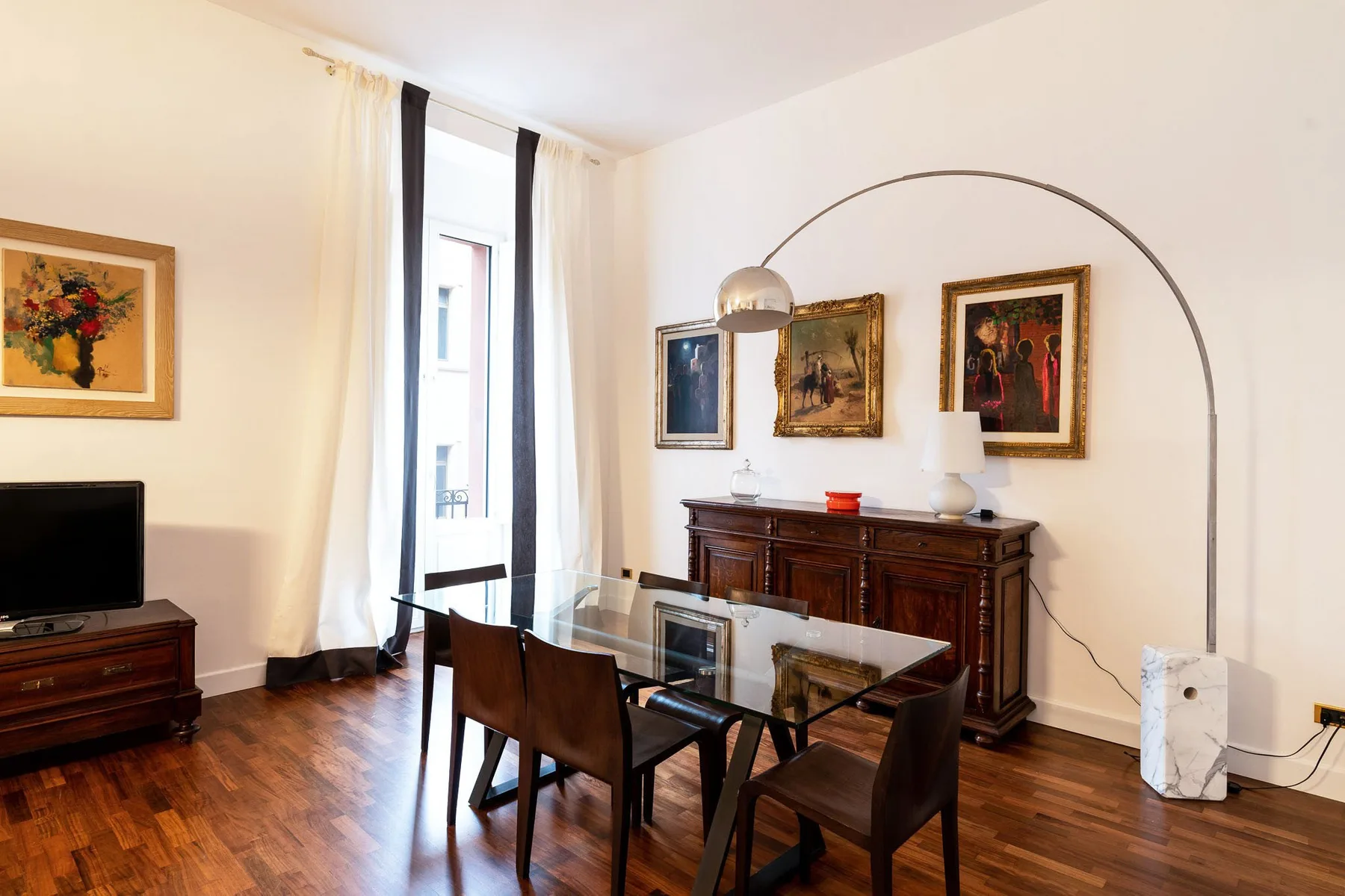 Un comedor y sala de estar con una mesa de cristal y muebles de madera oscura.