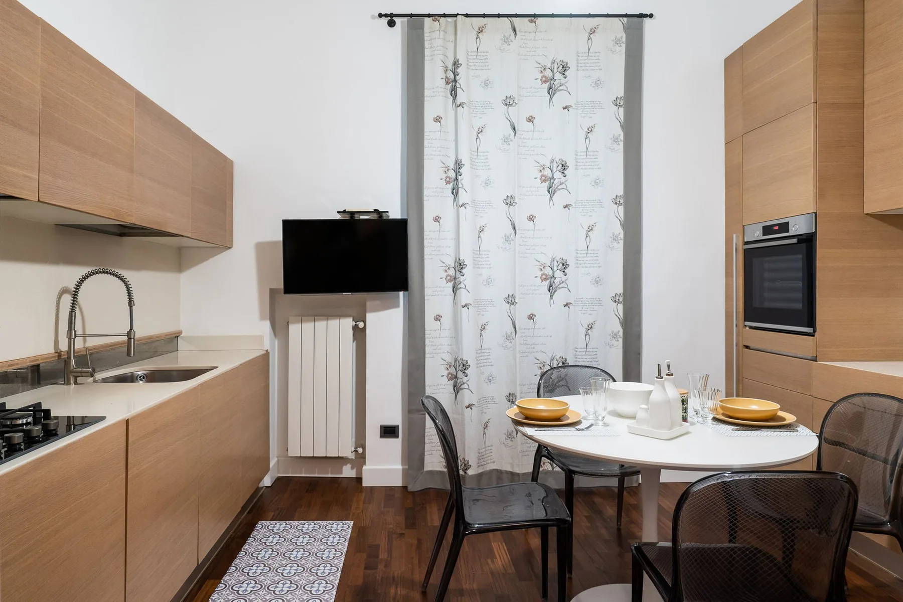 Cocina y comedor con armarios de madera, una placa de cocina y una mesa redonda.