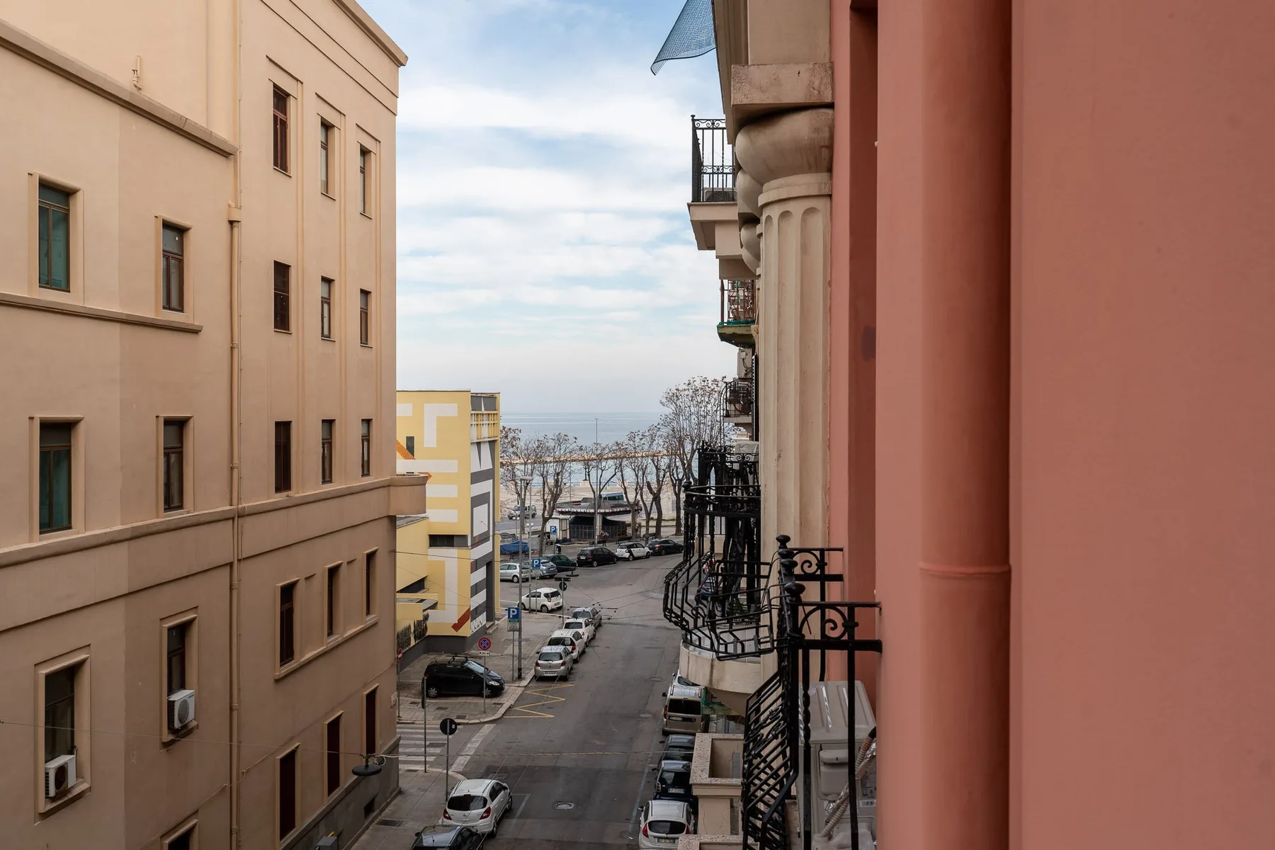 Una calle entre edificios de apartamentos conduce hacia una vista del mar.