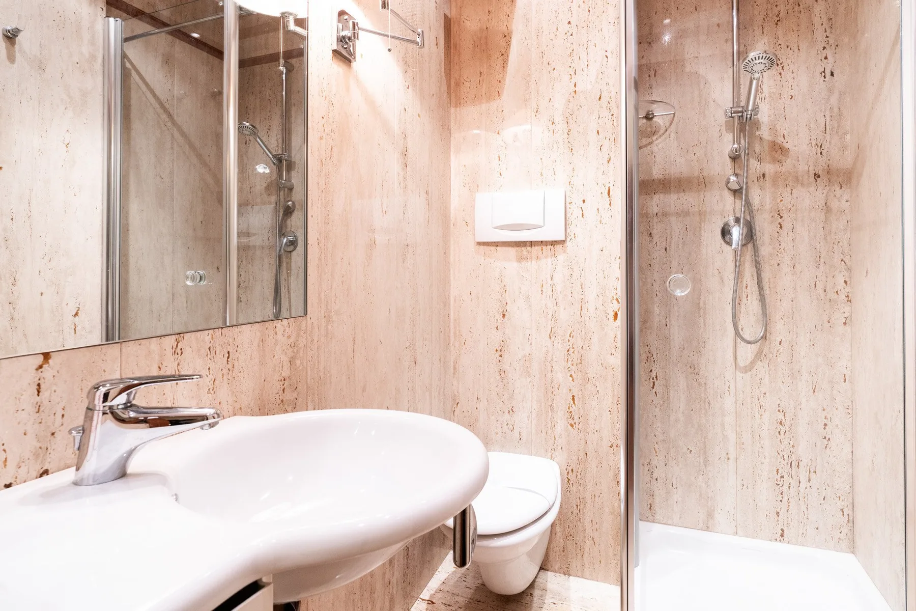 Un baño con un lavabo blanco y una ducha con mampara de vidrio.