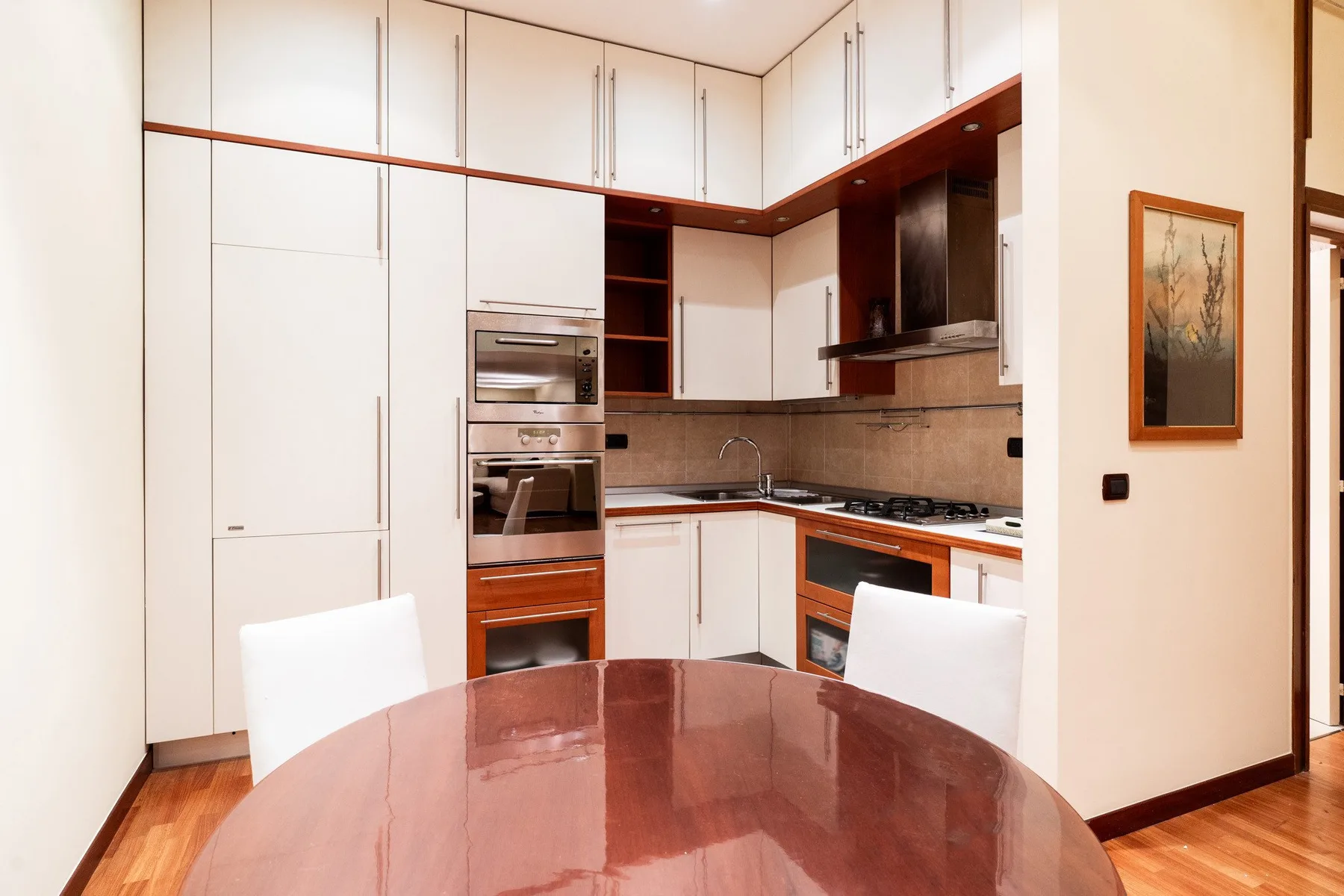 Una cocina moderna con armarios blancos y una mesa de comedor en primer plano.