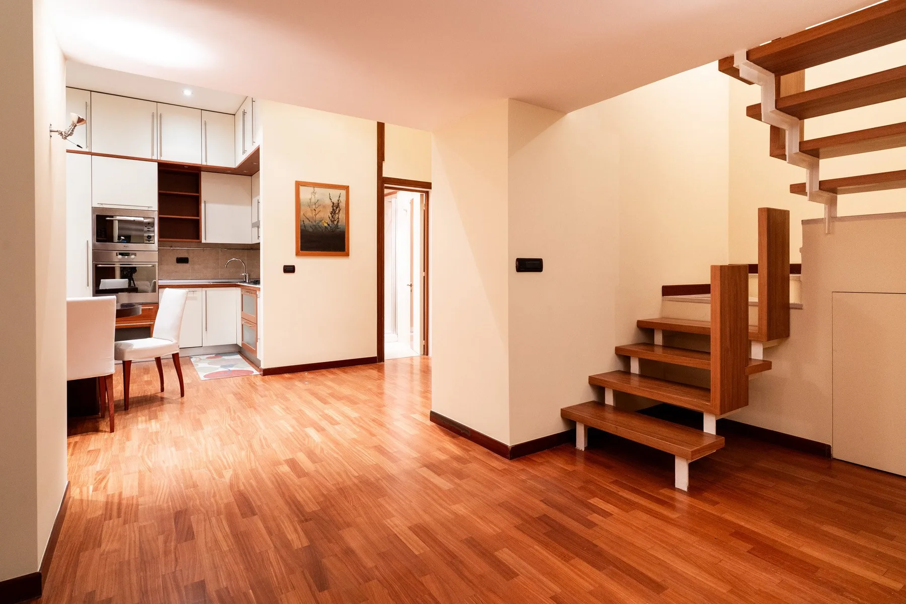 Cocina y comedor de planta abierta junto a una escalera de madera.