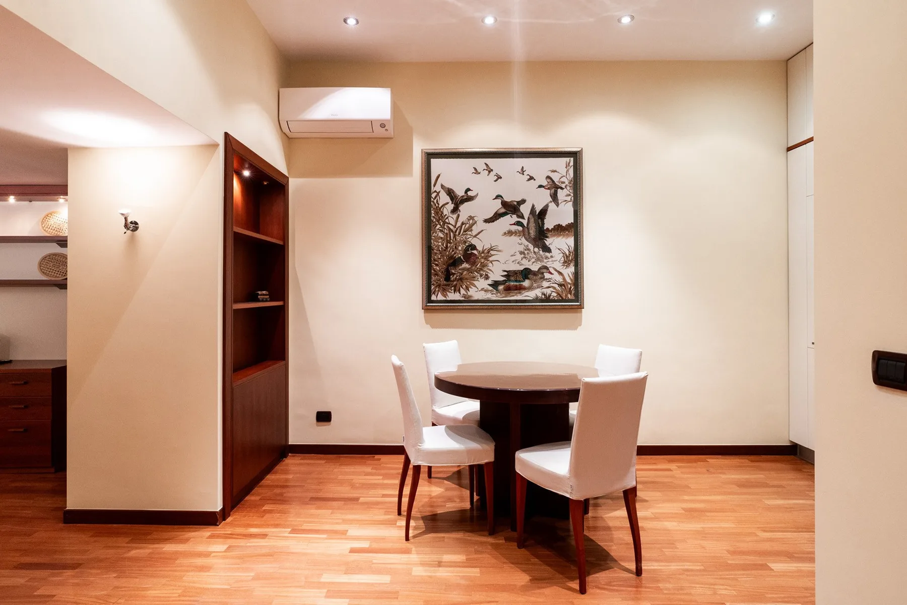 Comedor con una mesa redonda y sillas debajo de una obra enmarcada.