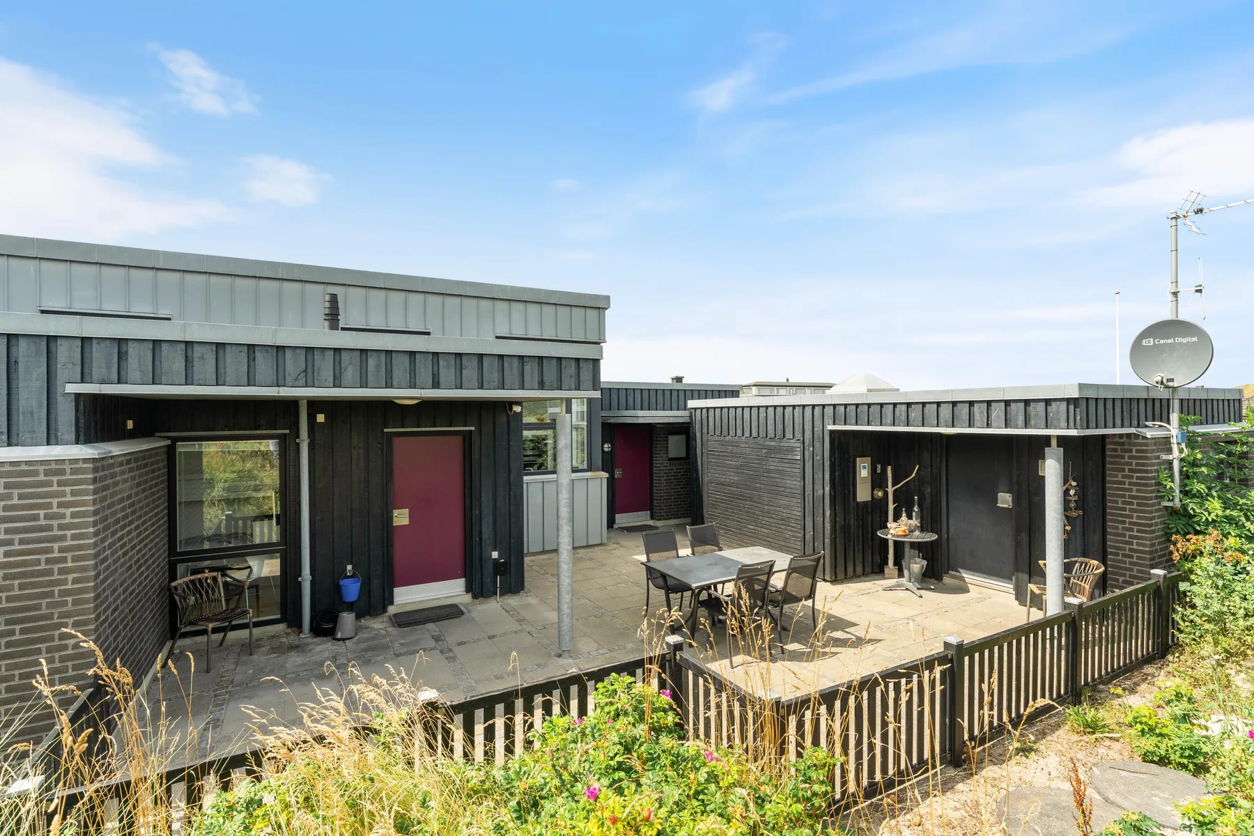 A modern house exterior with a paved patio and outdoor seating.