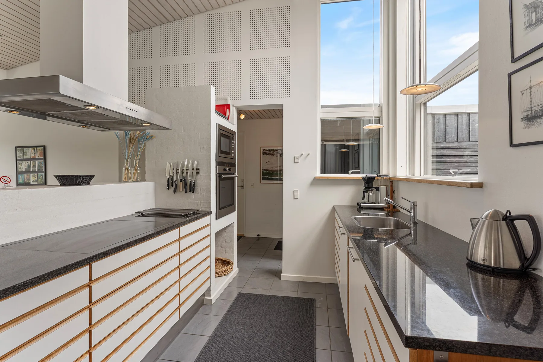 A bright kitchen with dark countertops, built-in appliances, and large windows.
