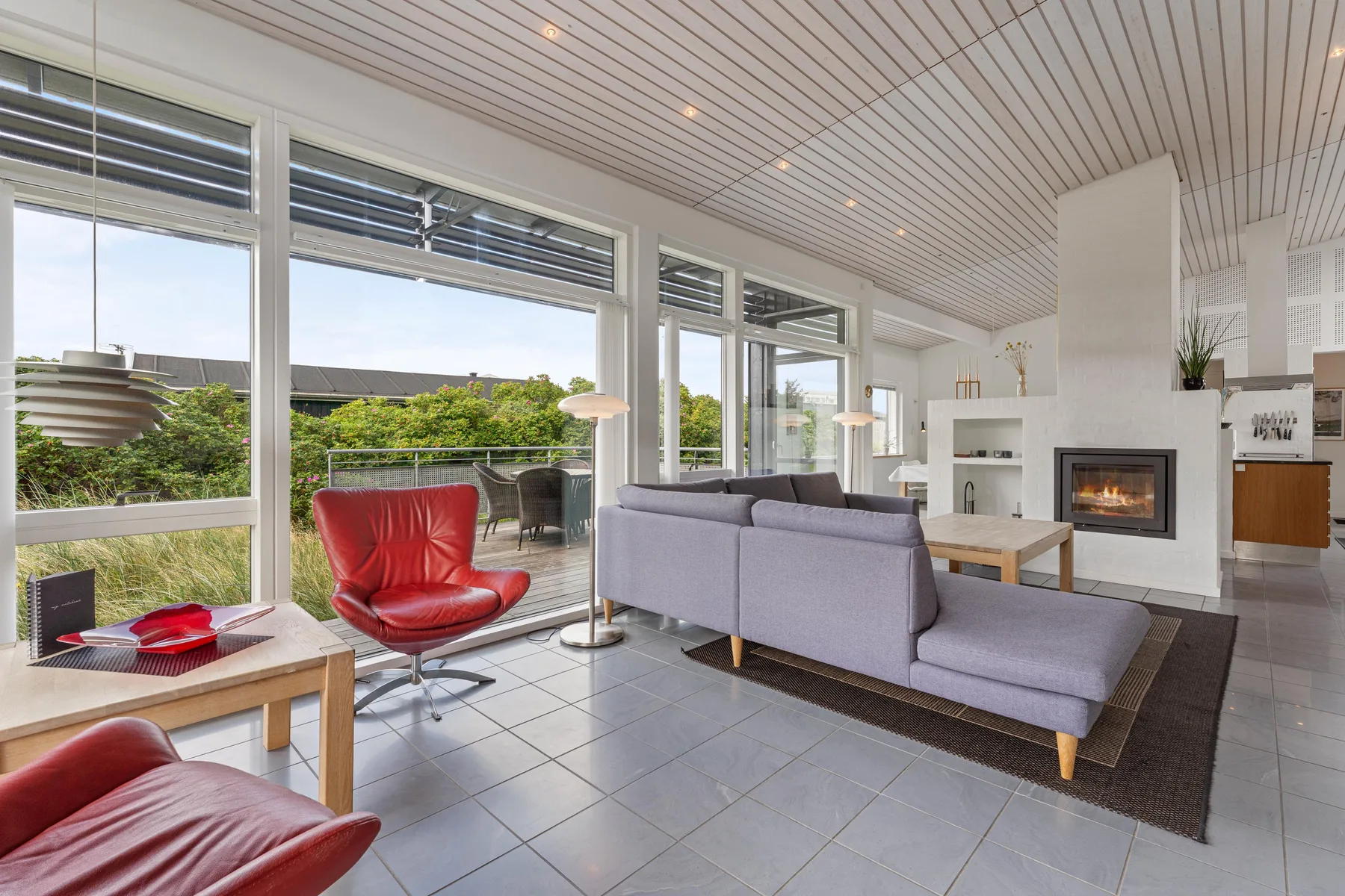A bright living room with seating, large windows, and a fireplace.