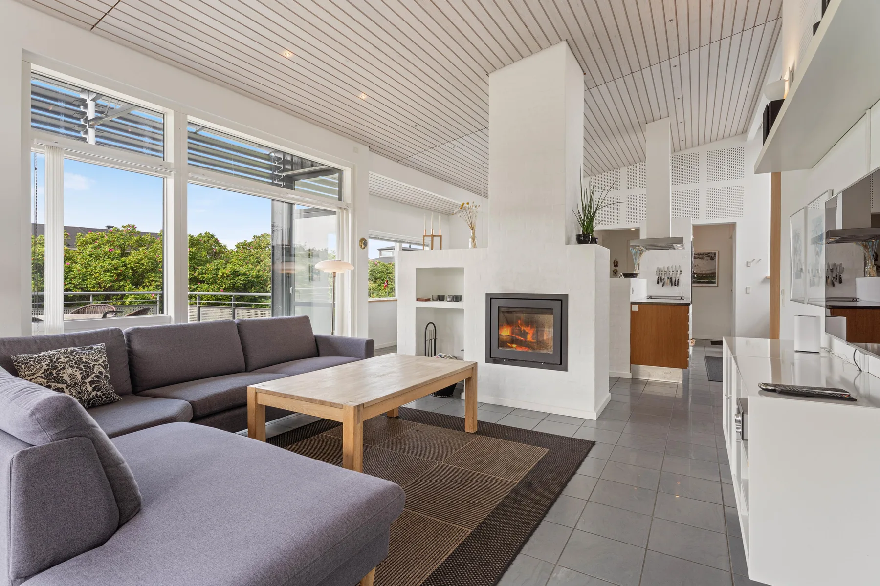 A bright living room with seating, a low table, and a fireplace.