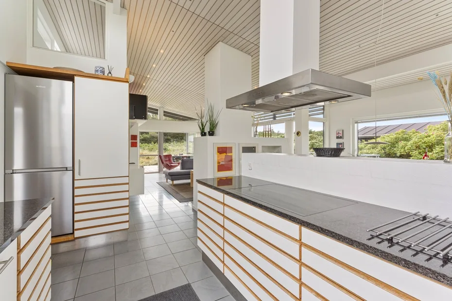 A bright modern kitchen with a large island and stainless-steel range hood.