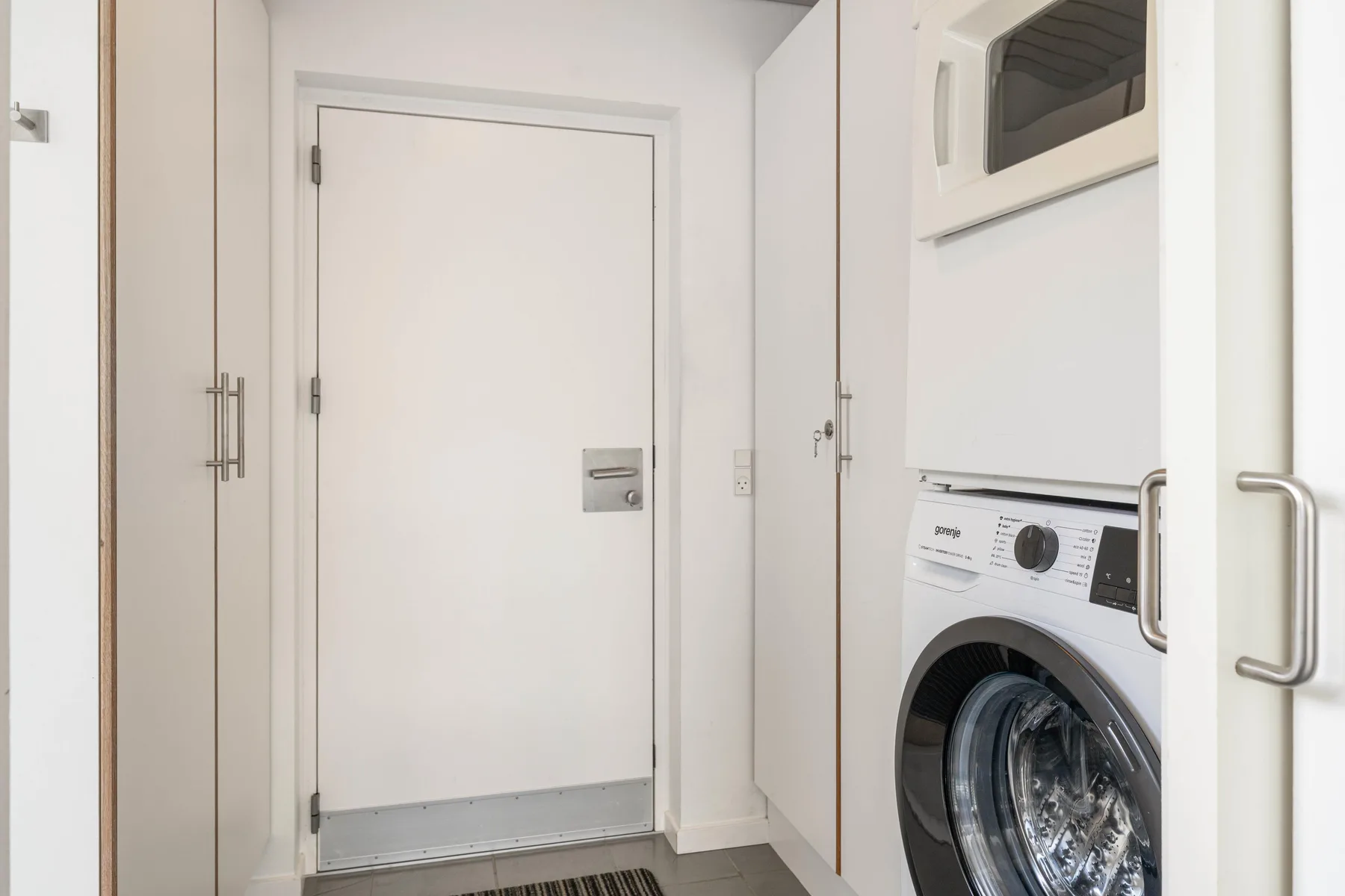 A laundry area with a front-loading washing machine beside a closed door.