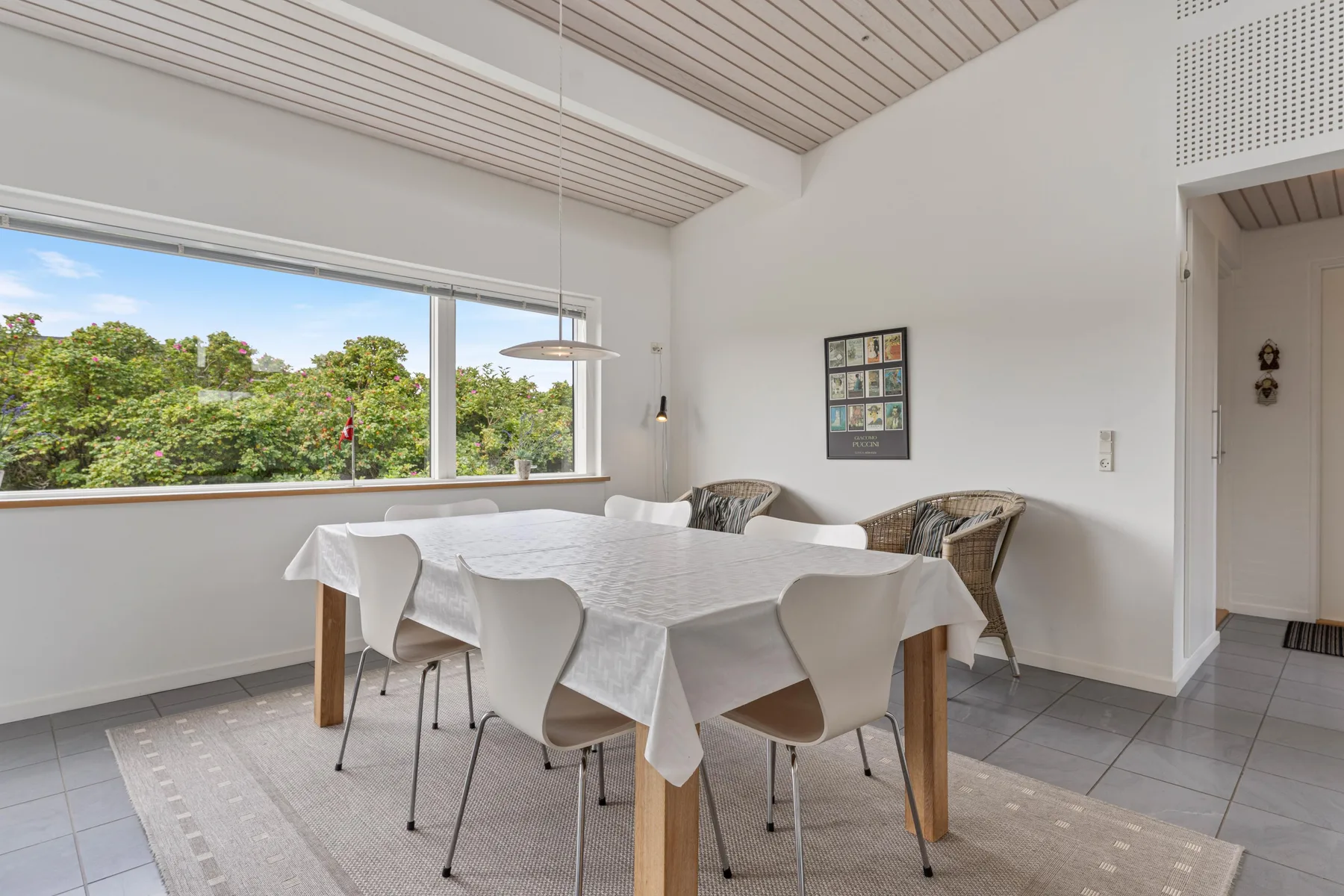 A dining area with a table and chairs beside a large window.
