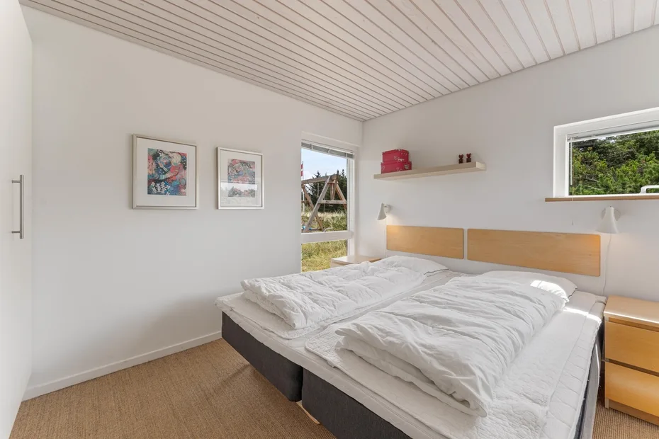 A bedroom with two beds, white bedding, and framed artwork on the wall.