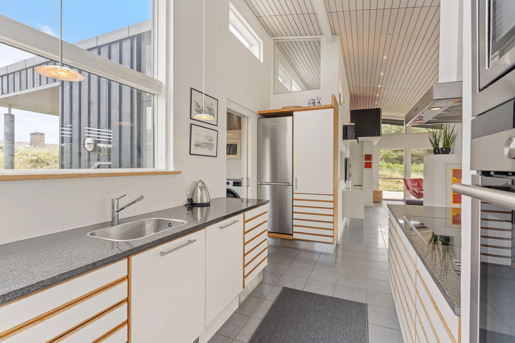 A bright kitchen with long countertops, a sink, and a window overlooking the outdoors.