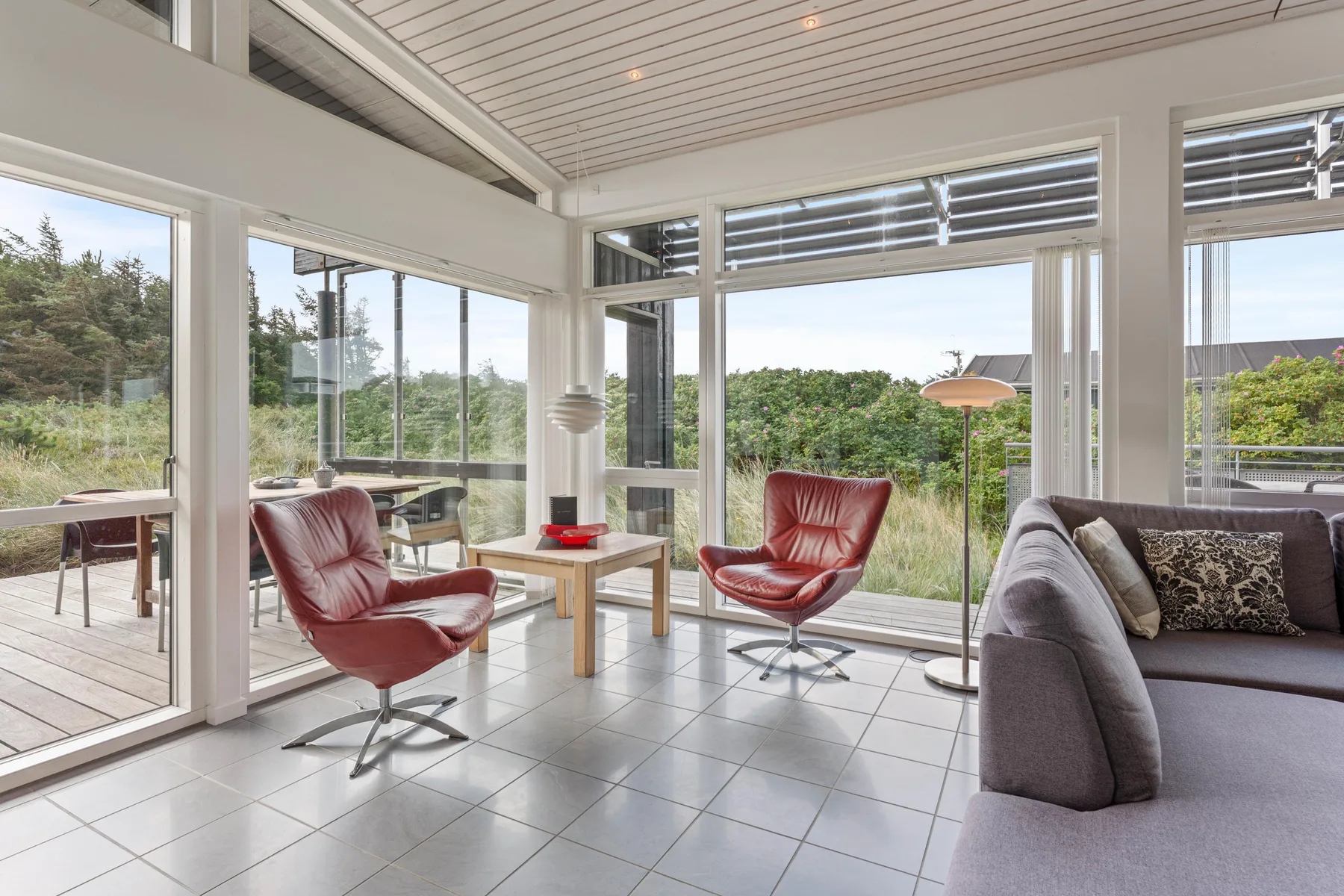 A bright living room with large windows and seating overlooking greenery.