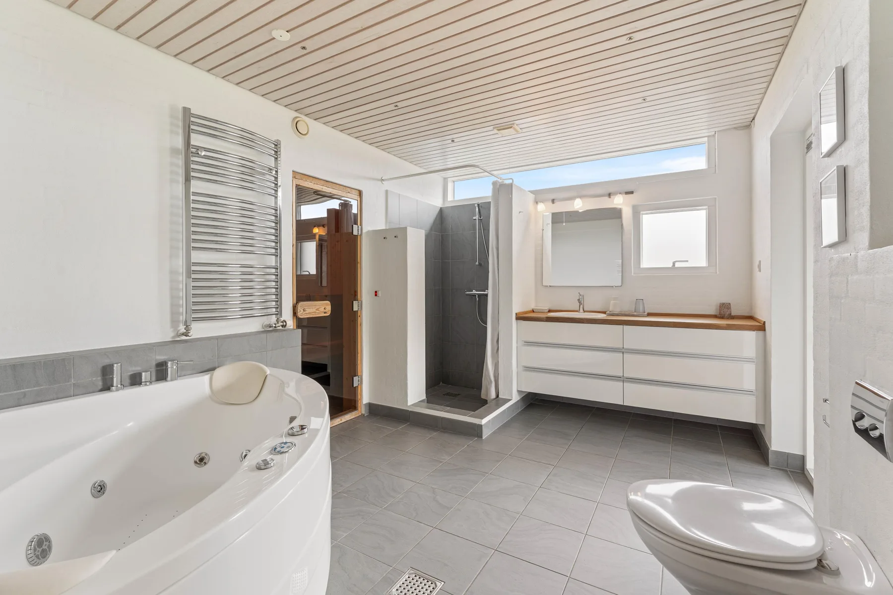 A spacious bathroom with a bathtub, shower, and vanity.