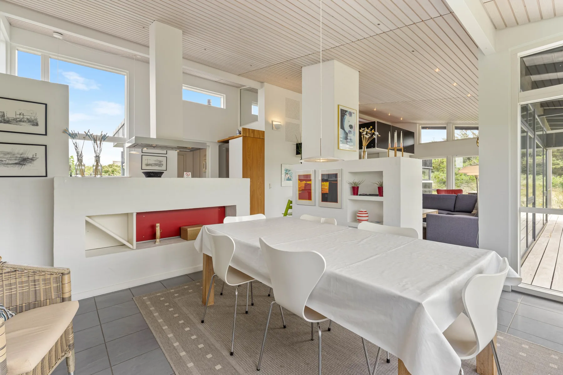A bright open-plan dining area with a long table beside the living space.