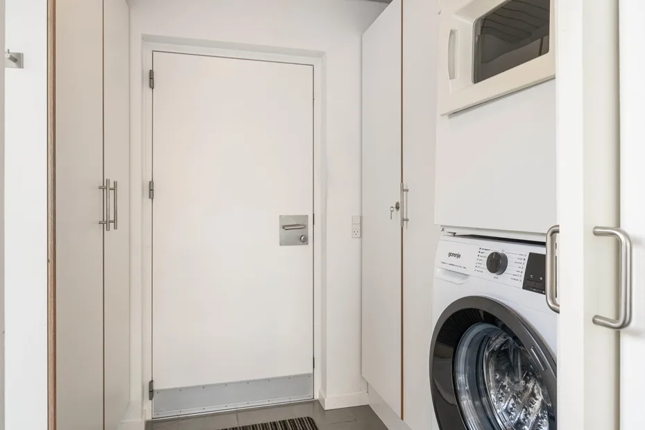 A laundry area with a front-loading washing machine beside a white door.