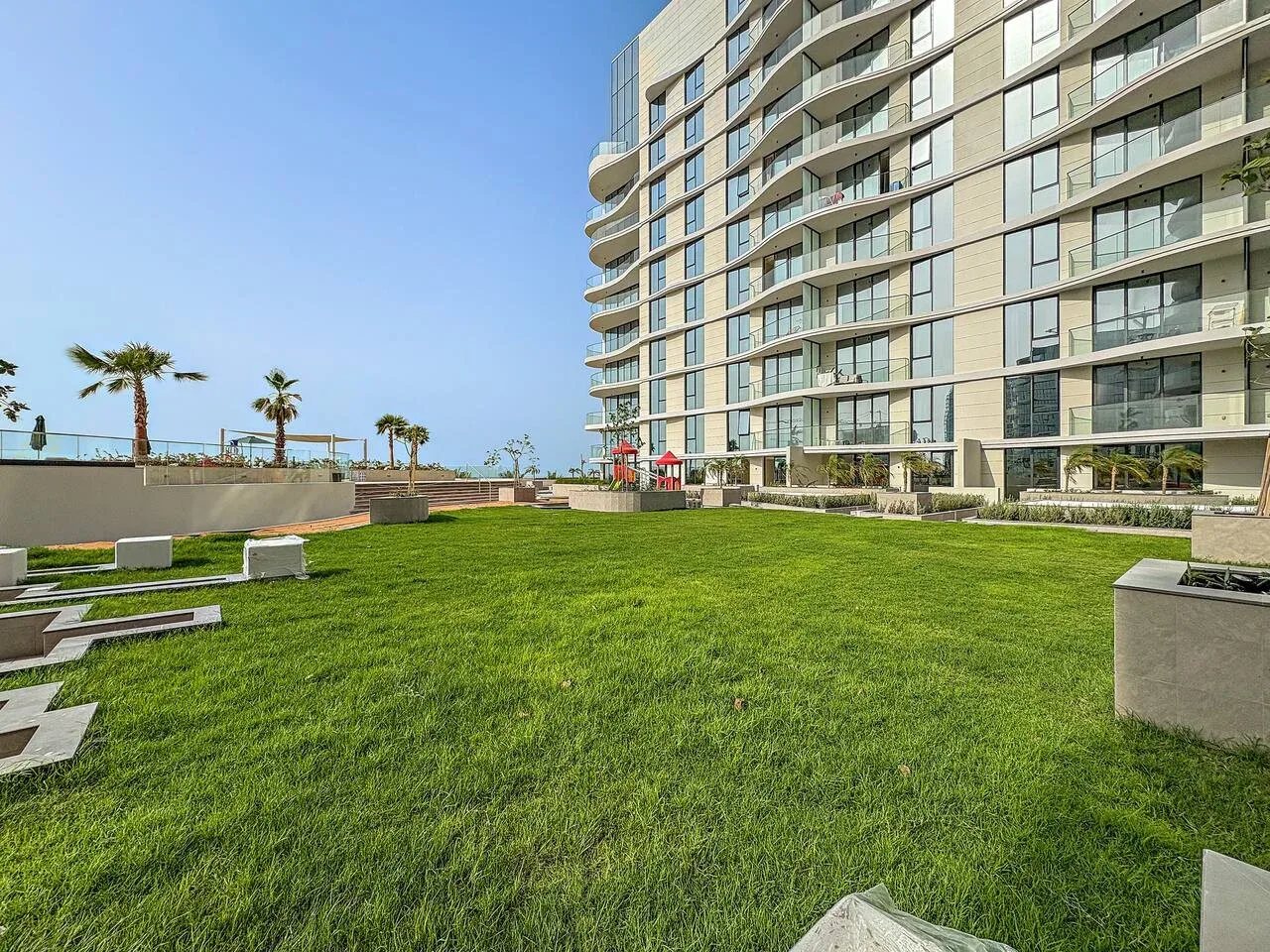 A landscaped lawn and seating area beside a modern apartment building.