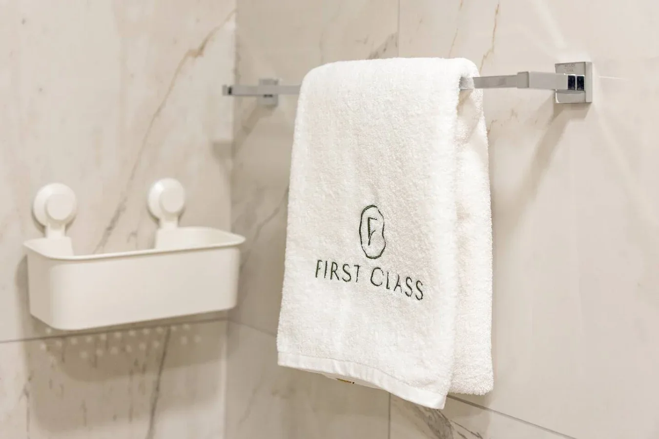 A bathroom wall with a white towel hanging above a wall-mounted holder.