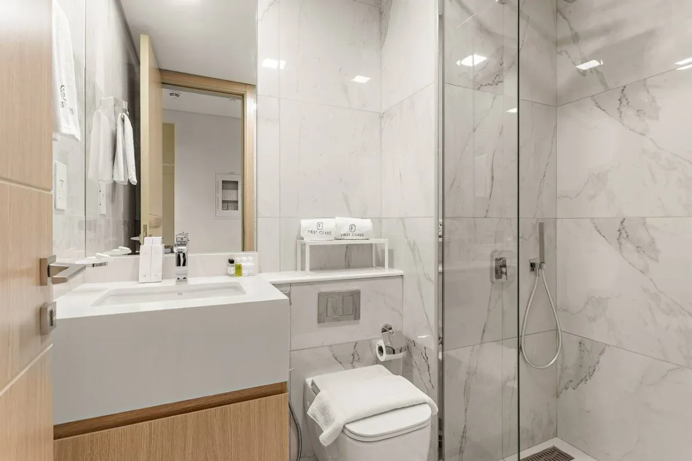 A bright bathroom with a sink, toilet, and glass shower.
