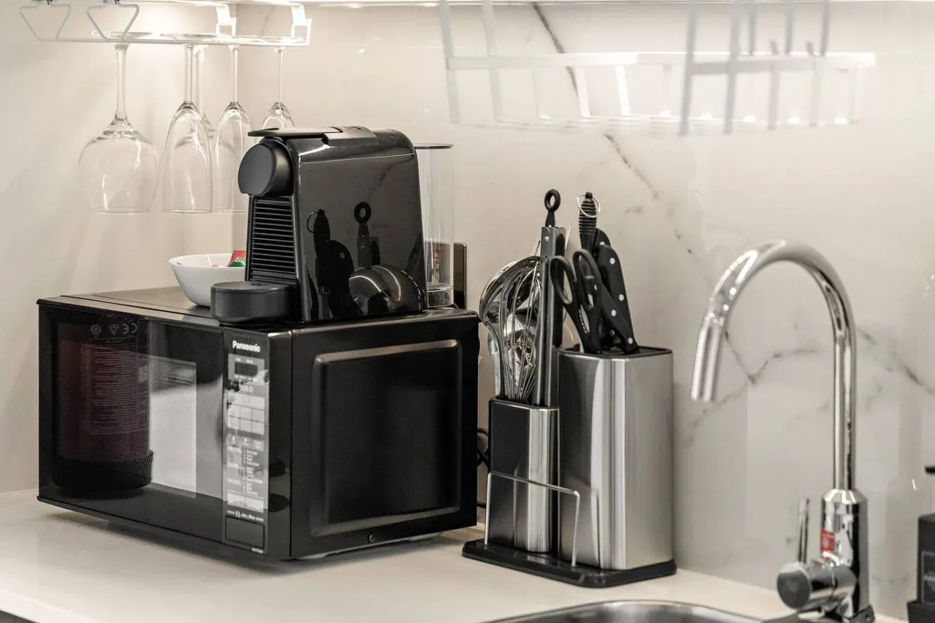 A kitchen counter with a coffee machine, microwave, and utensils.