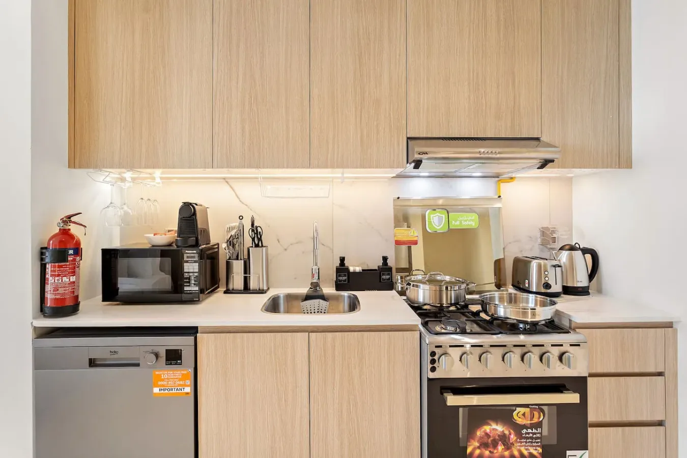 Cocina con gabinetes de madera clara, electrodomésticos sobre la encimera y estufa.