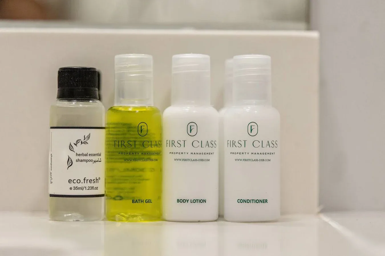 Toiletries arranged on a bathroom counter, including shampoo, bath gel, lotion, and conditioner.