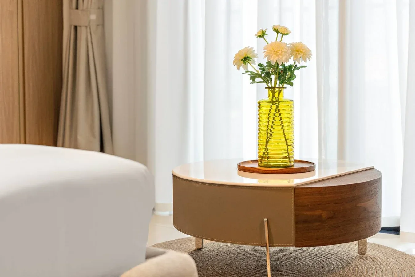 A curved coffee table with a vase of flowers sits beside seating.