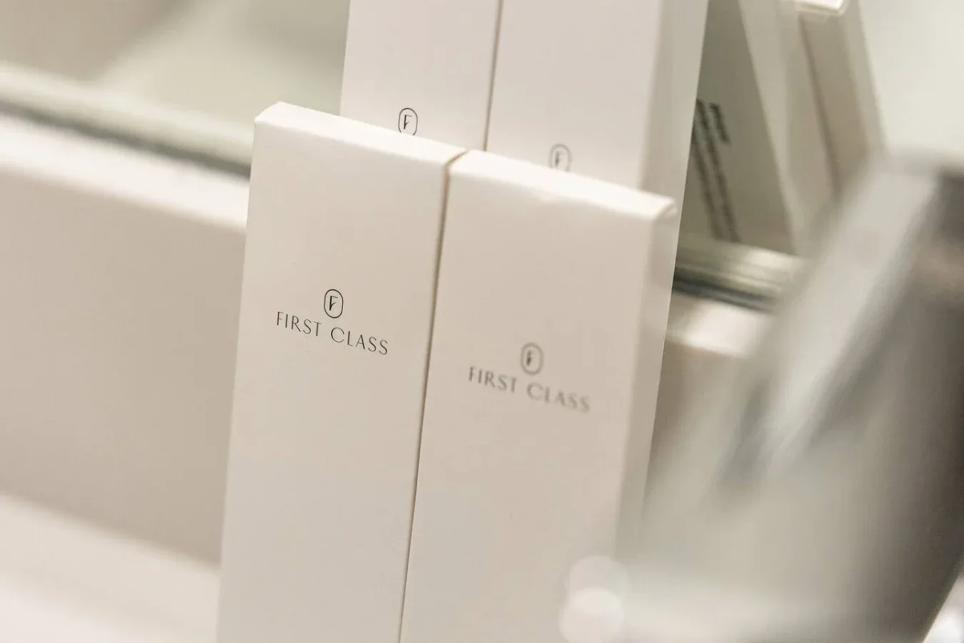 White First Class amenity boxes sit beside a bathroom mirror.