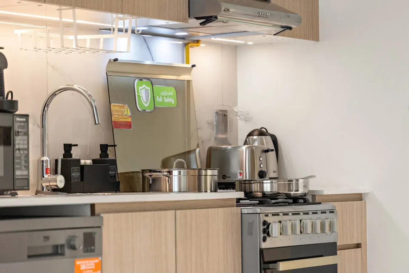 A kitchen counter with cooking appliances and a kettle beneath a range hood.