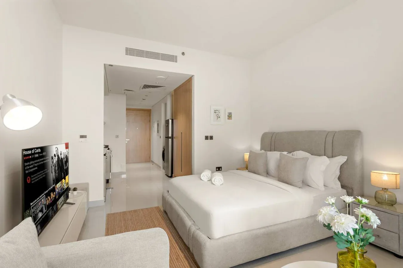 A bedroom with a neatly made bed, bedside tables, and a television.