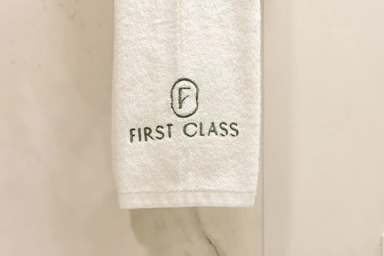 A white towel hangs against a light-colored wall.