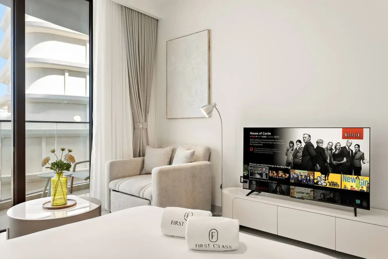 Un dormitorio luminoso con una cama, una pequeña zona de estar y un televisor.