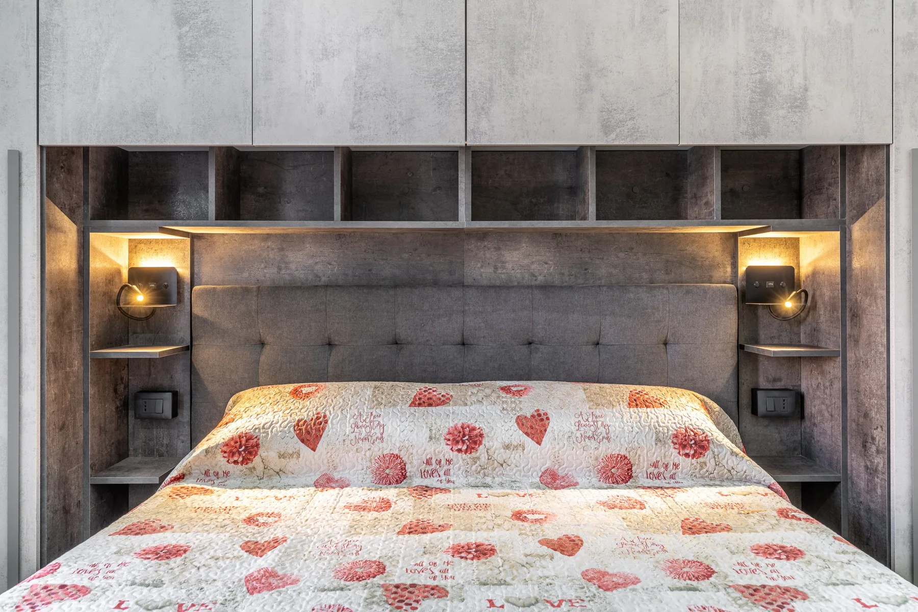 Un dormitorio con una cama cubierta con ropa de cama floral y estantes empotrados.