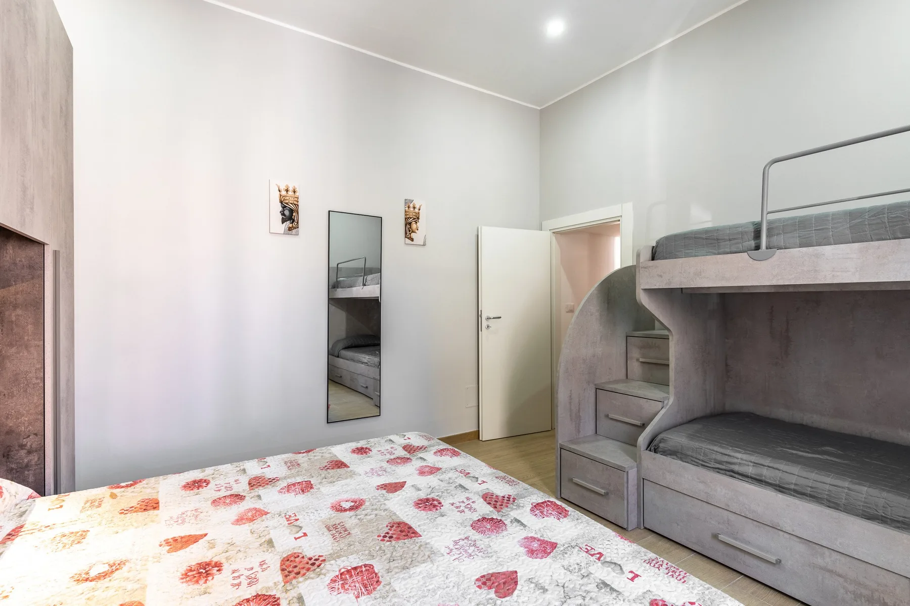 Un dormitorio con literas y una cama cubierta con una colcha estampada.