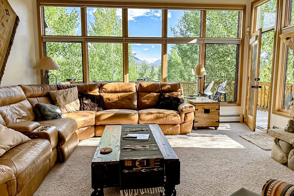 A living room with leather seating, a coffee table, and large windows.