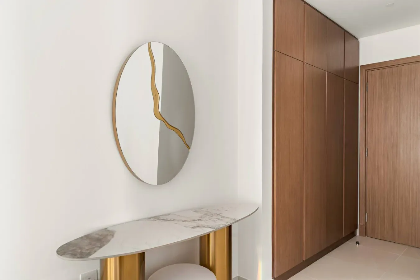 A bright entry area with a round wall mirror above a narrow console table.