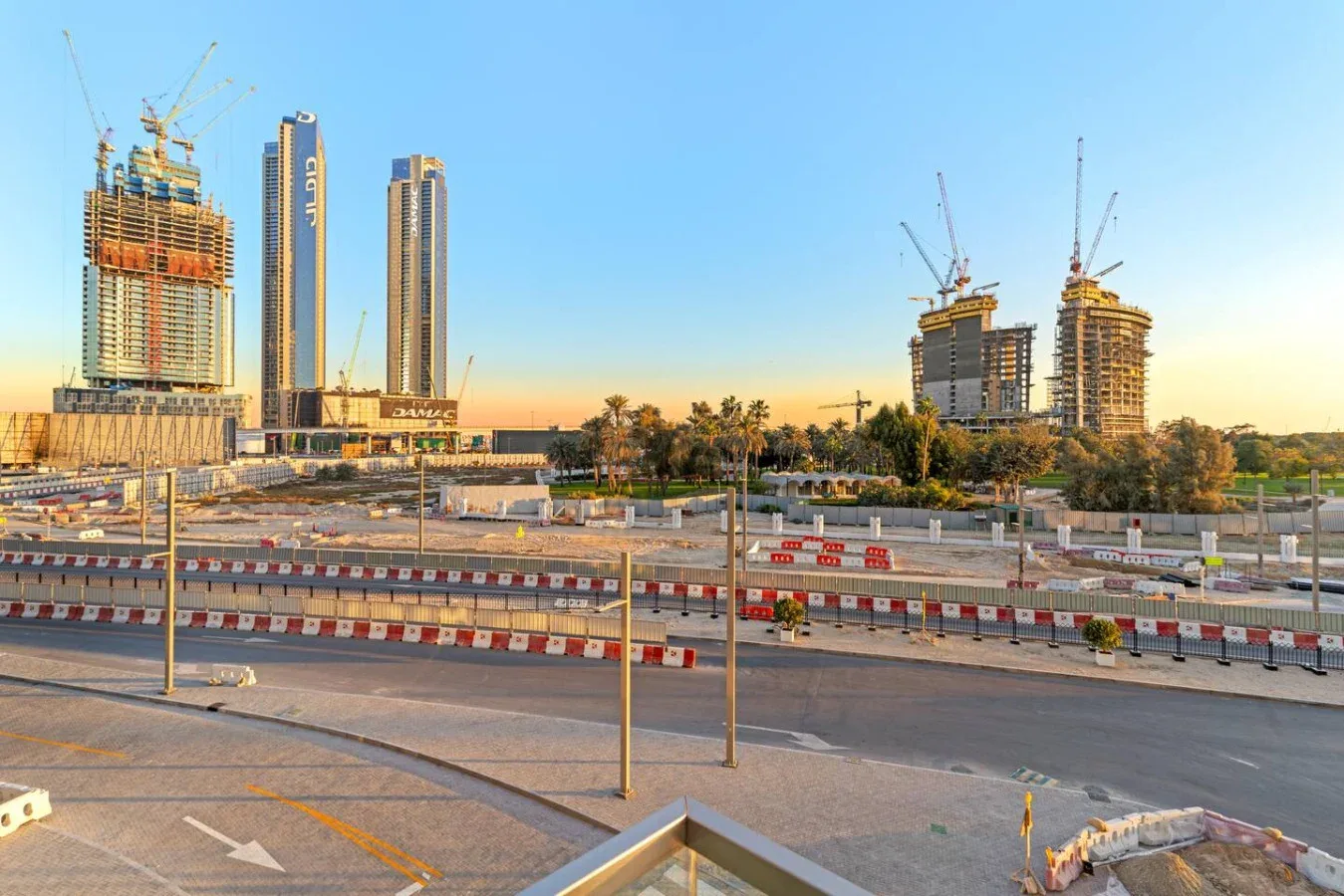 A construction site with several tall buildings and cranes beneath a clear sky.