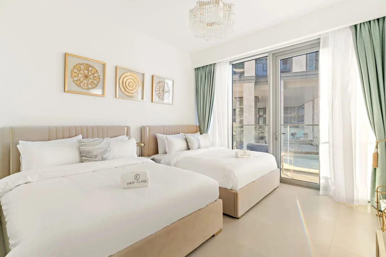 A bright bedroom with two beds and large windows framed by curtains.