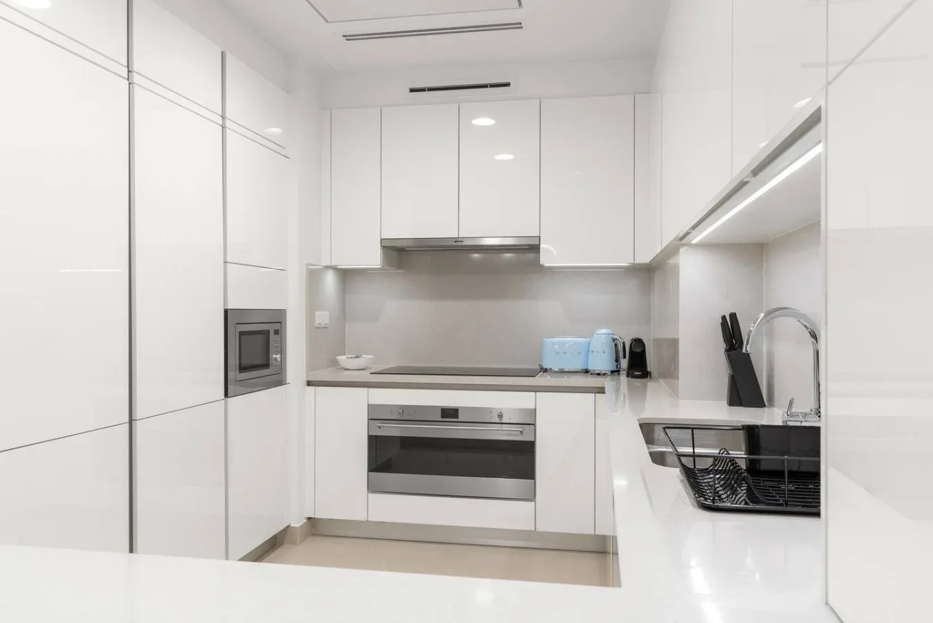 A bright modern kitchen with white cabinets and a countertop.