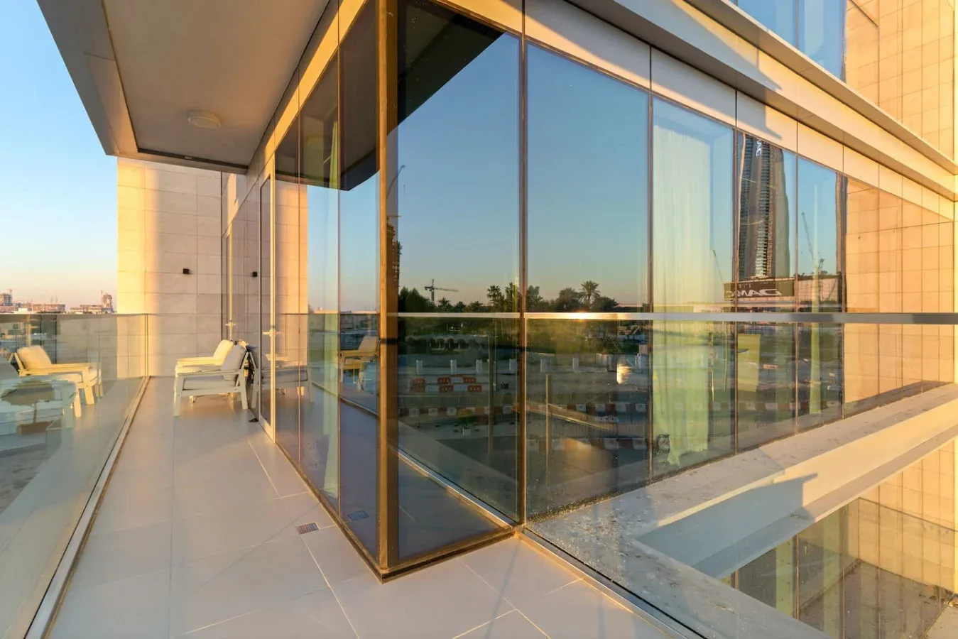 A glass-walled terrace with tiled flooring and outdoor seating overlooks the surrounding city.