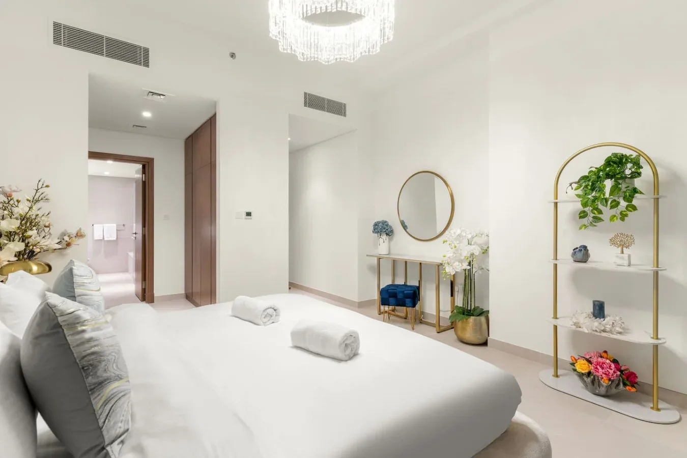 A bright bedroom with a neatly made bed and decorative shelving.