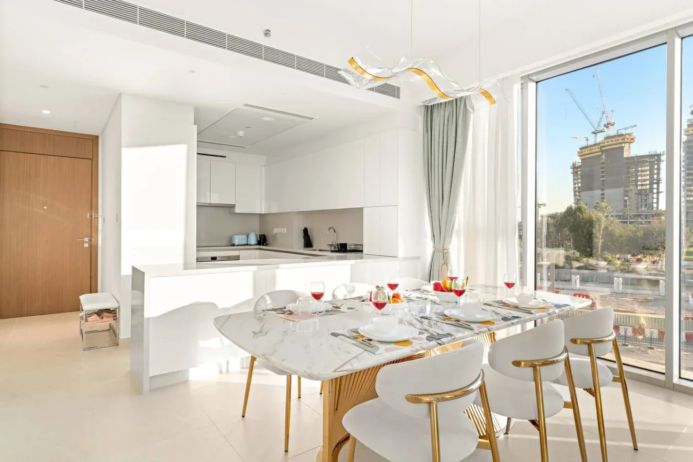 A bright dining area with a set table beside large windows and an open kitchen.