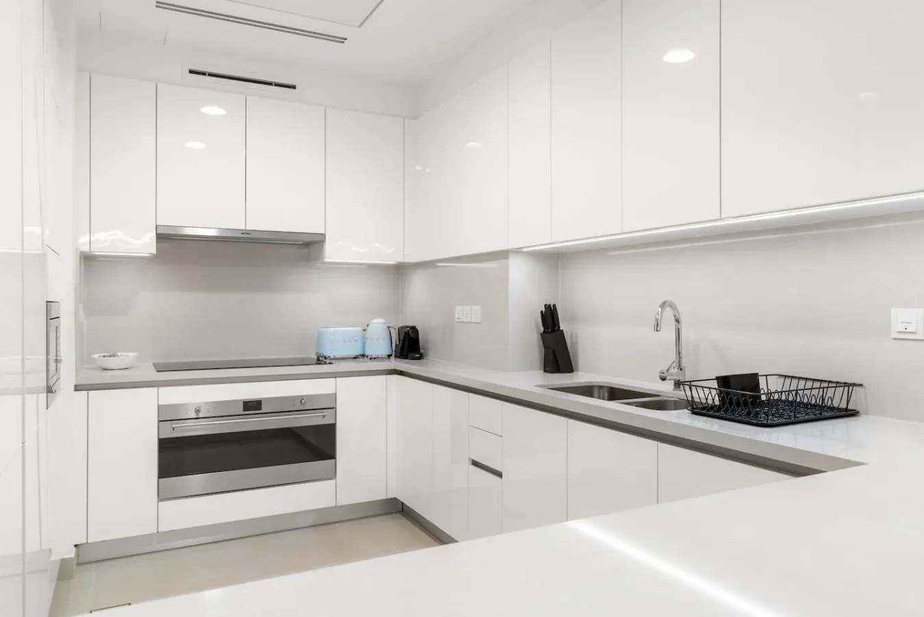 A bright white kitchen with an oven, countertop, and sink.