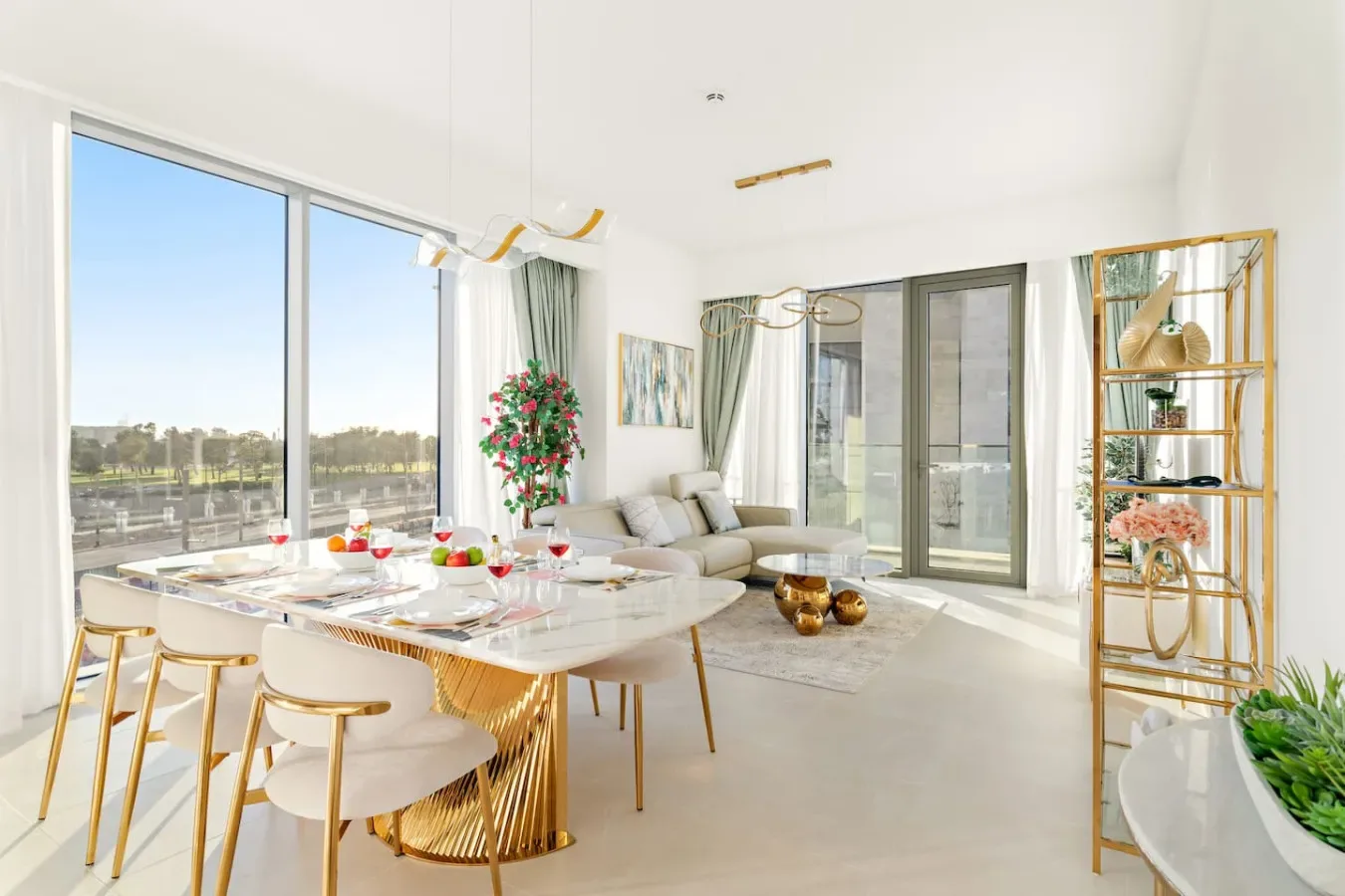 A bright open-plan living and dining area with large windows and a set table.